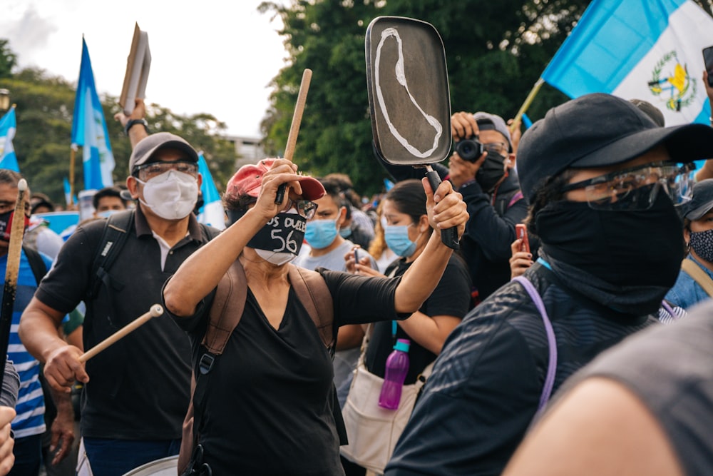 man in black shirt wearing mask holding brown stick