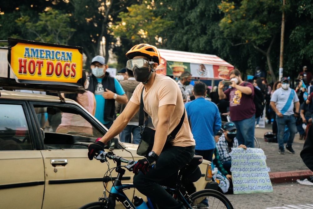 man in brown tank top riding on black bicycle during daytime