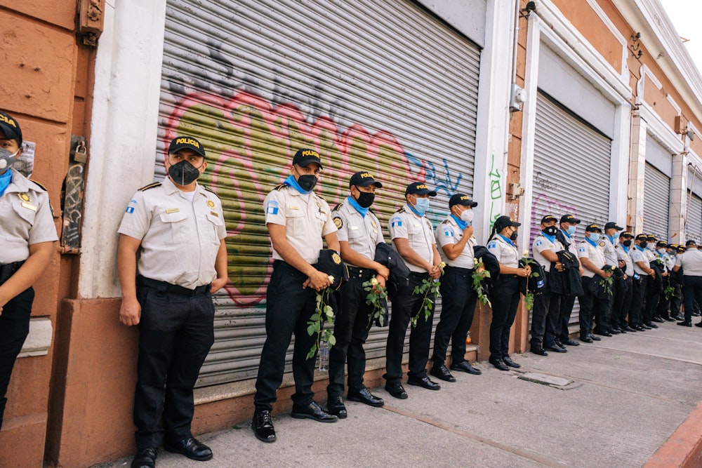 hombre en polo blanco de pie junto a hombre en pantalones de camuflaje verde y negro durante el día