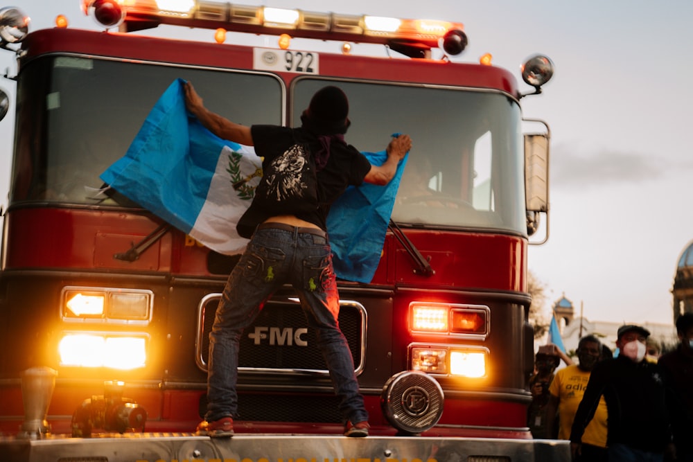 Hombre en chaqueta negra y pantalones negros sentado en camión rojo