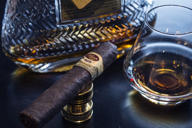 Close-up of a premium cigar resting on a dark wooden table with warm golden lighting.