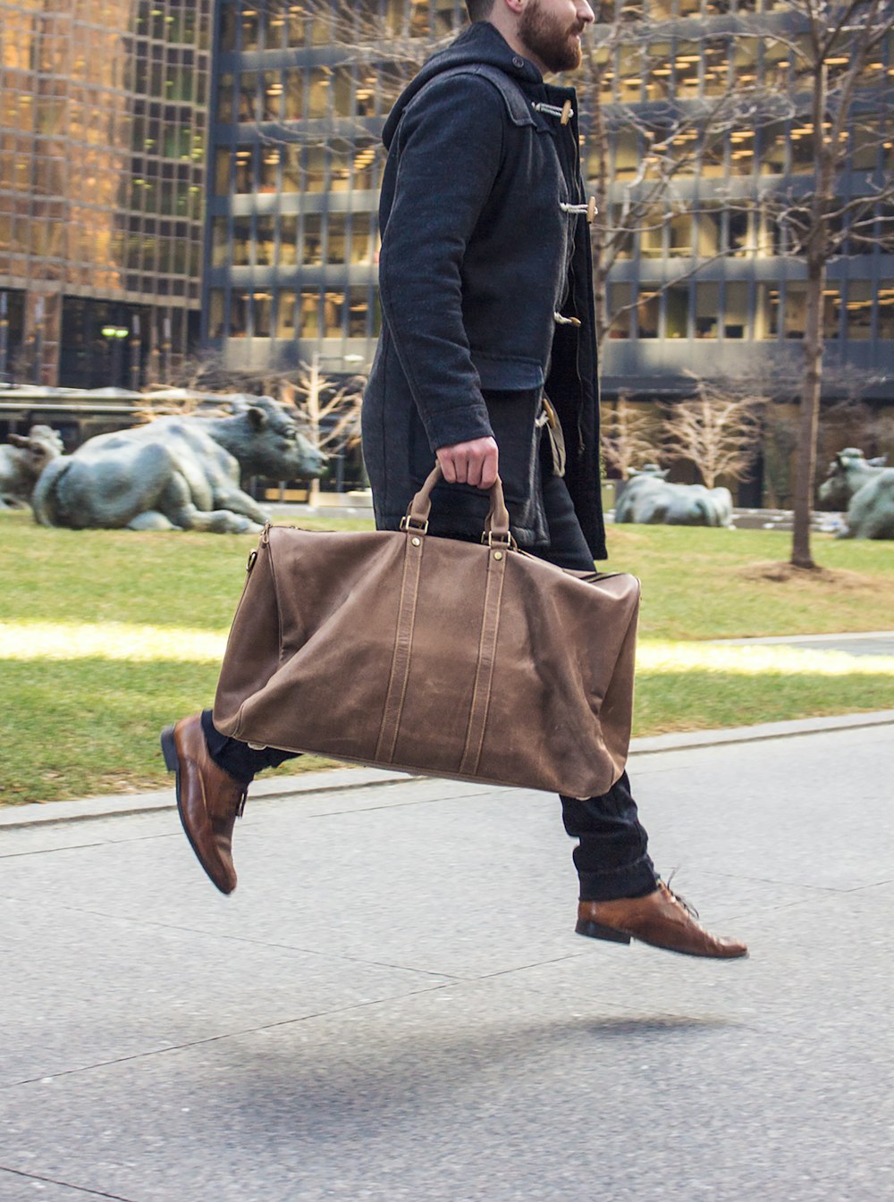 person in black pants and brown leather sling bag walking on sidewalk during daytime