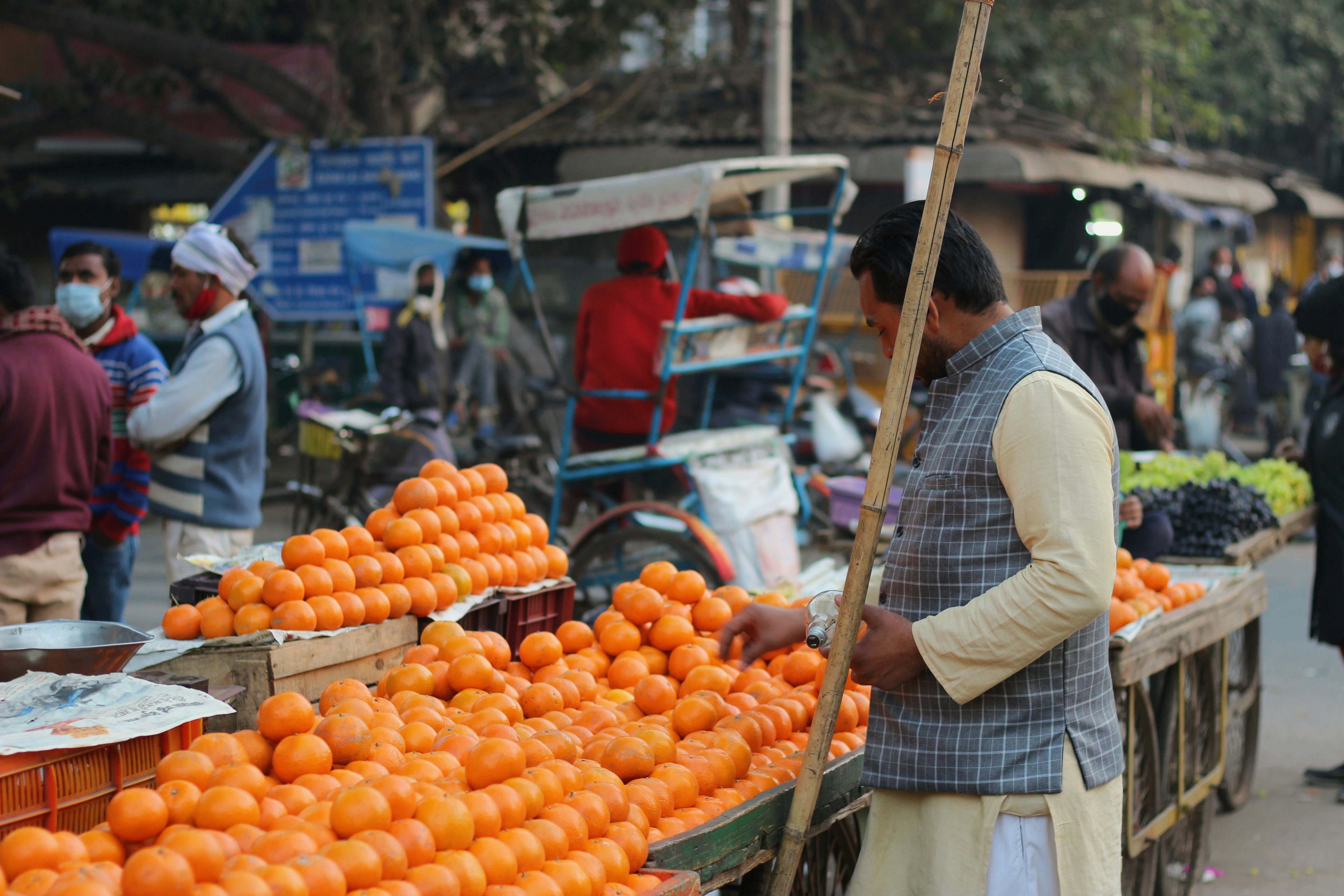 man in white and black plaid dress shirt holding a basket of orange fruits