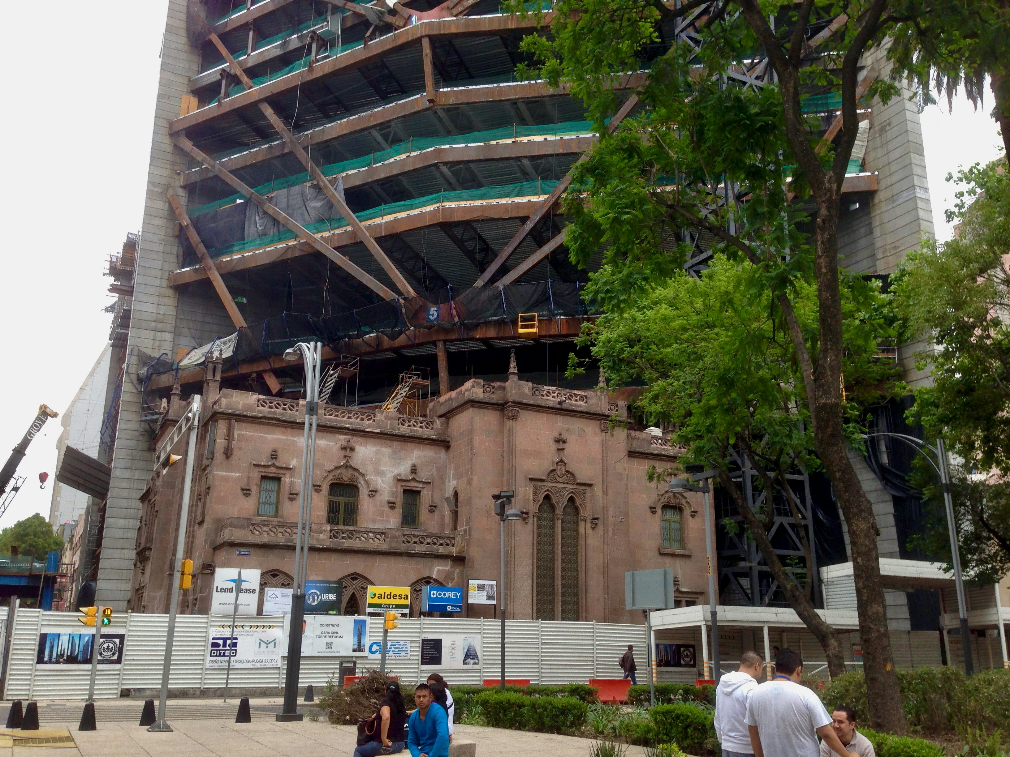 Large commercial building steel frame under construction with exposed I-beams and columns against overcast sky