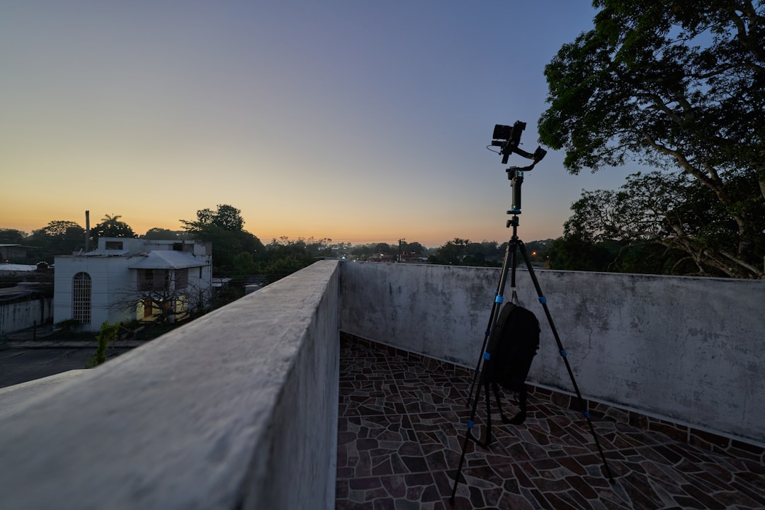 black camera on tripod on gray concrete wall during sunset