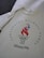 A cream-colored T-shirt displays the logo for the 1996 Atlanta Centennial Olympic Games featuring a stylized flame in red with stars above it and the Olympic rings below, surrounded by text.