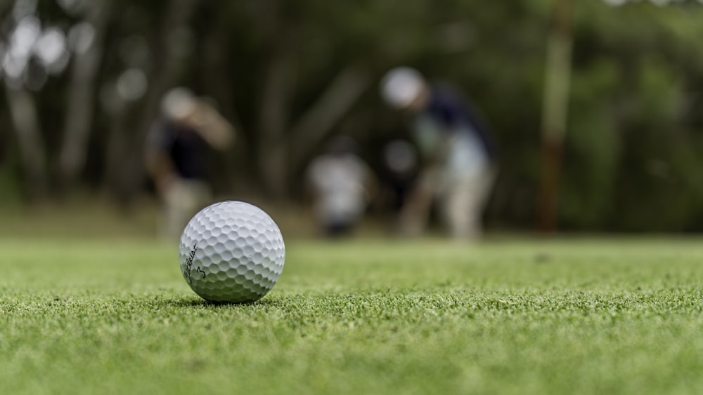 weißer Golfball auf grünem Rasen tagsüber