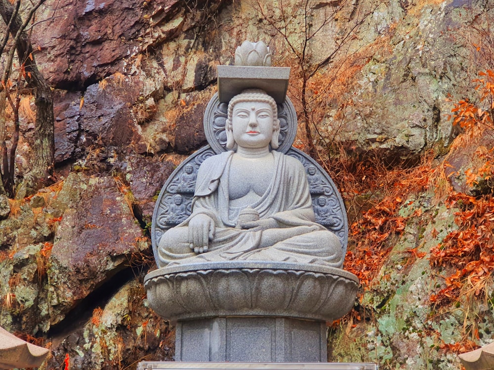 gray concrete statue near brown and red leaves