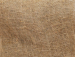 Close-up of a jute sack with a custom printed golden logo on a graphite gray background.