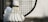 A close-up view of a shuttlecock leaning against a badminton racket with a focus on the net and feathers. The background is blurred, emphasizing the sports equipment in the foreground.