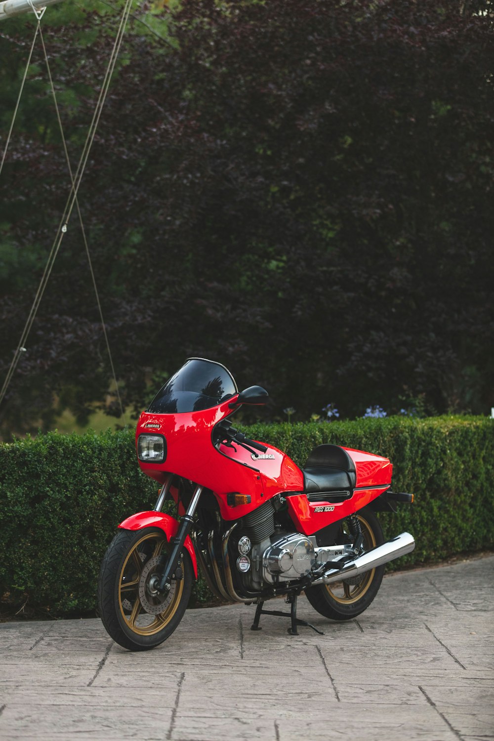 red and black motorcycle parked on green grass field during daytime