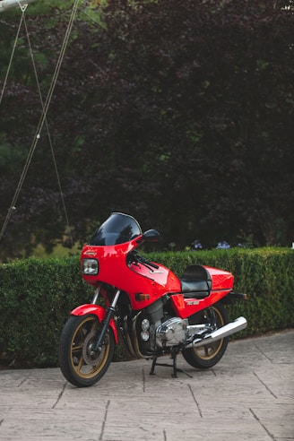 red and black motorcycle parked on green grass field during daytime