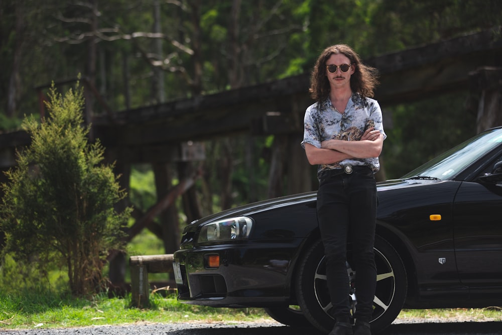 woman in white shirt and black pants sitting on black car