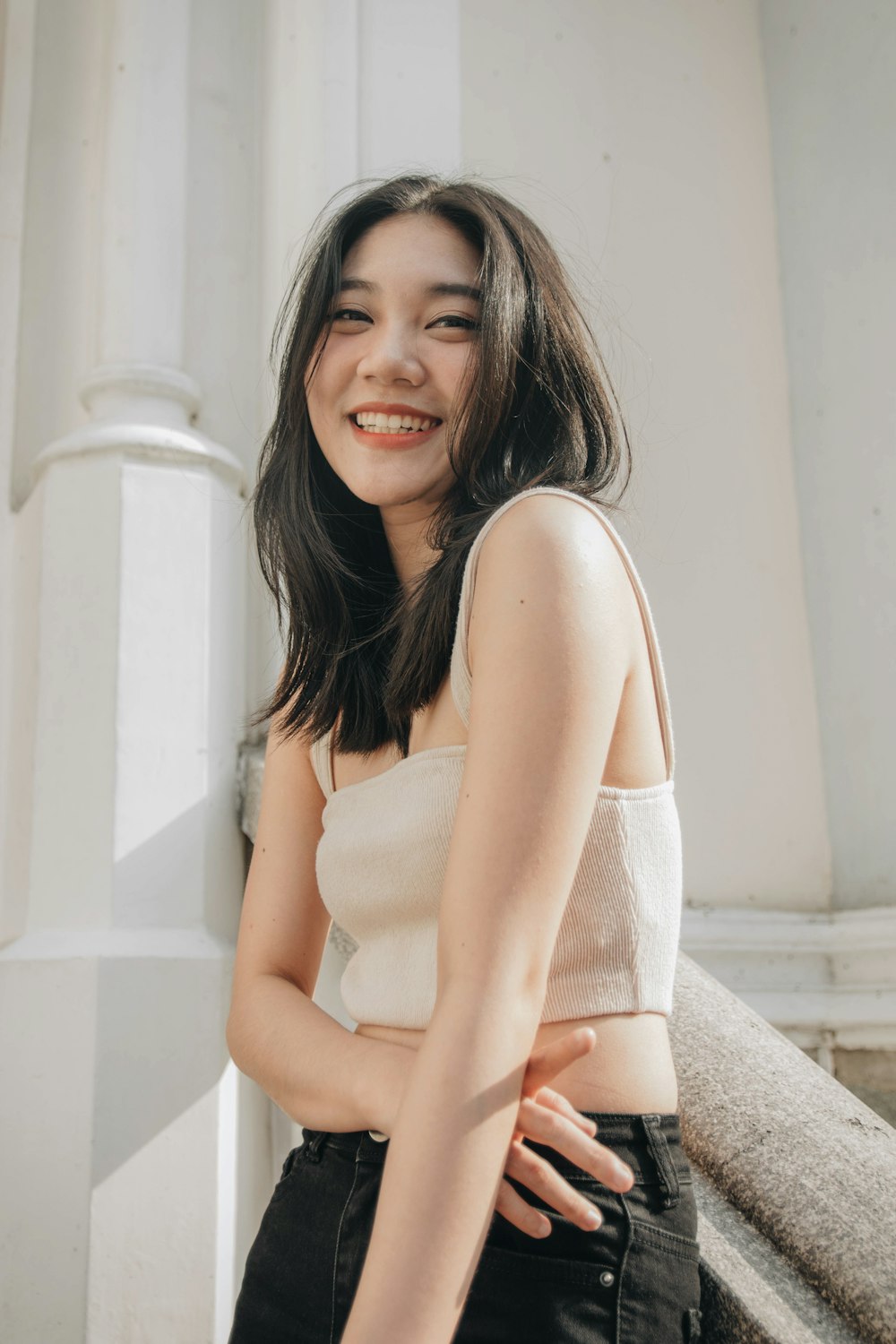 woman in white tank top sitting on white concrete staircase