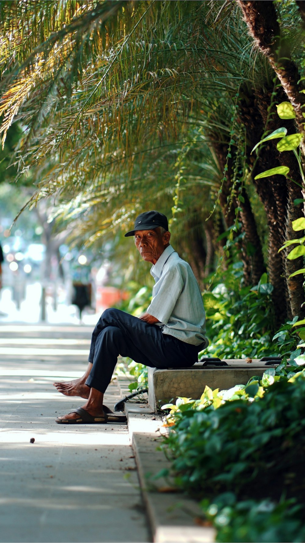 man in white dress shirt and black pants sitting on bench during daytime