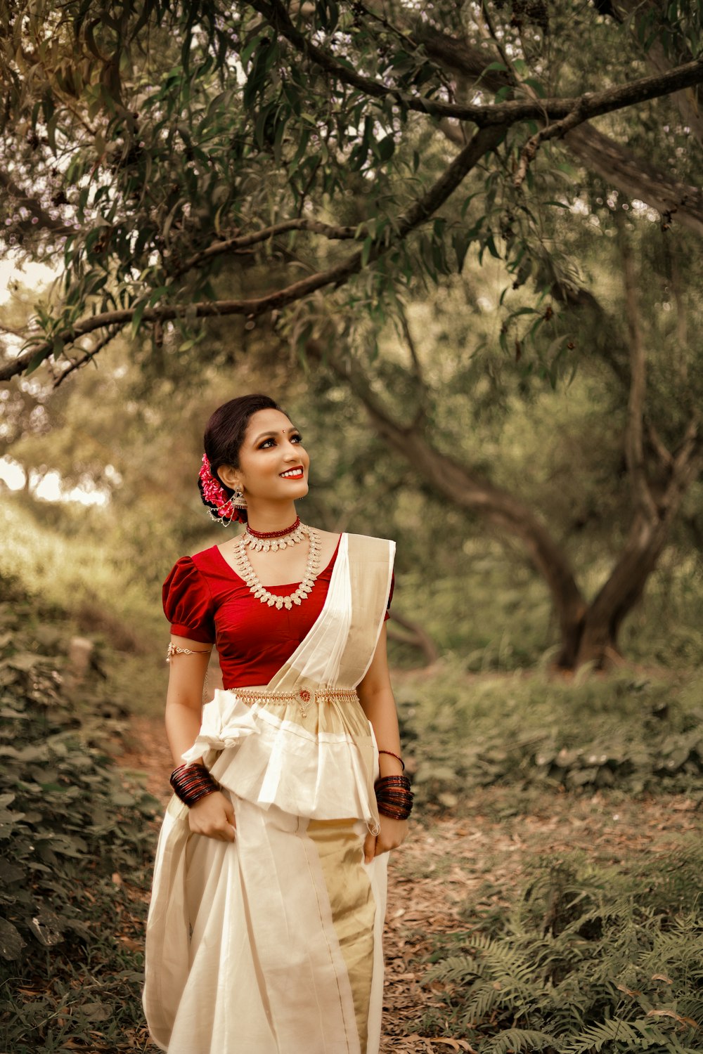 woman in red and white dress standing near trees during daytime