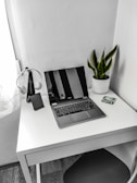 A minimalist workspace featuring a tablet, headphones, and a small potted plant.