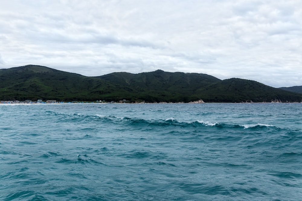 body of water near mountain during daytime