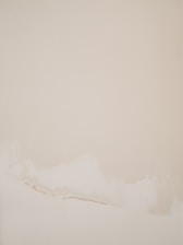 An abstract painting with soft, muted colors hanging elegantly in a minimalist living room.