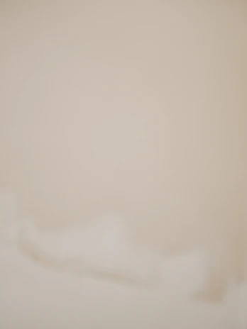 Soft beige abstract shapes layered with subtle shadows creating a warm, textured background.