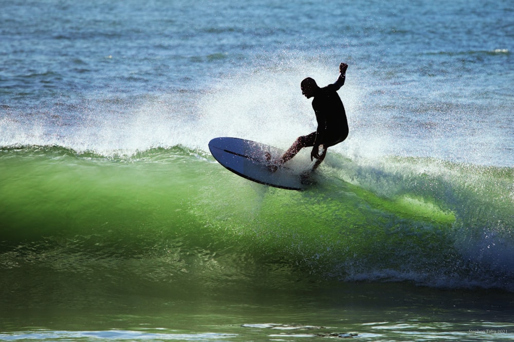 man in black wet suit surfing on sea waves during daytime