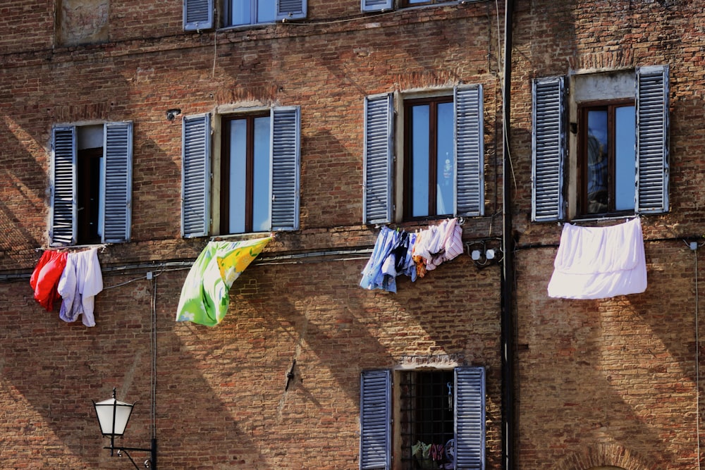 clothes hanged on wire near brown brick building during daytime