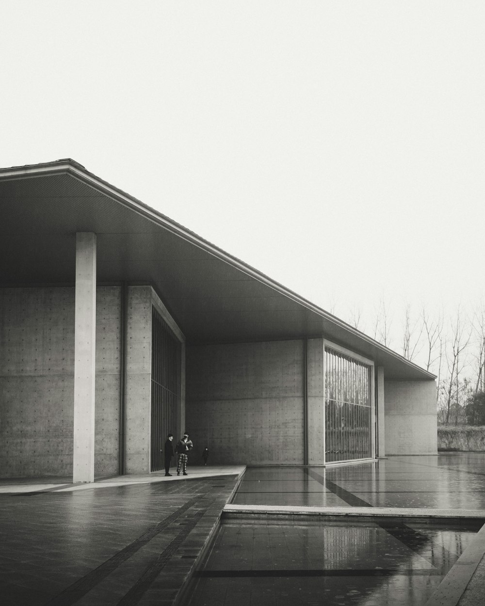 grayscale photo of a man standing in front of a building