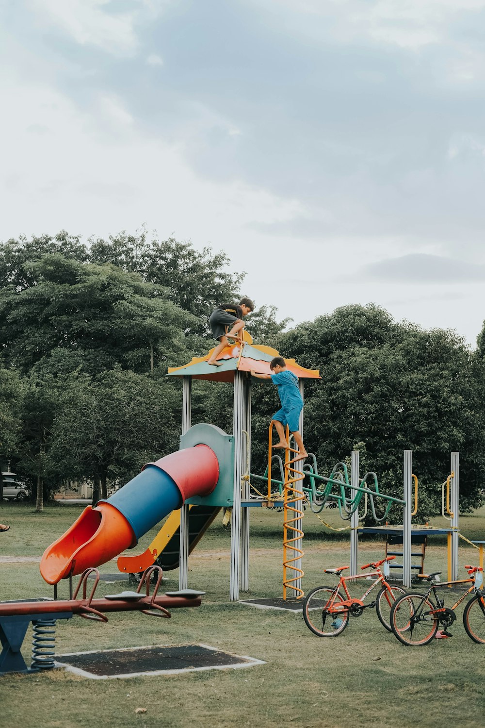 girl in yellow shirt and blue denim shorts sitting on blue and red slide