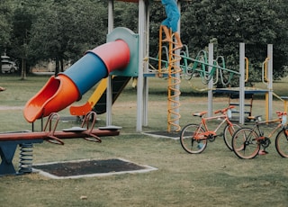 girl in yellow shirt and blue denim shorts sitting on blue and red slide