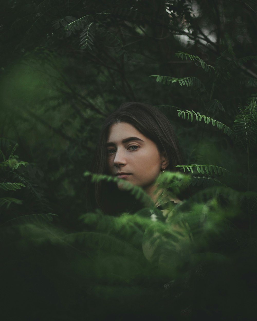 woman in green long sleeved shirt surrounded by green leaves