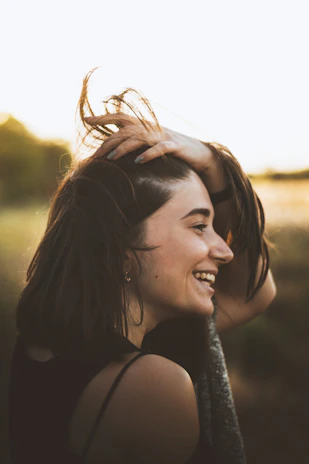 Happy patient with shiny, healthy hair after hair fall treatment, smiling in natural light.