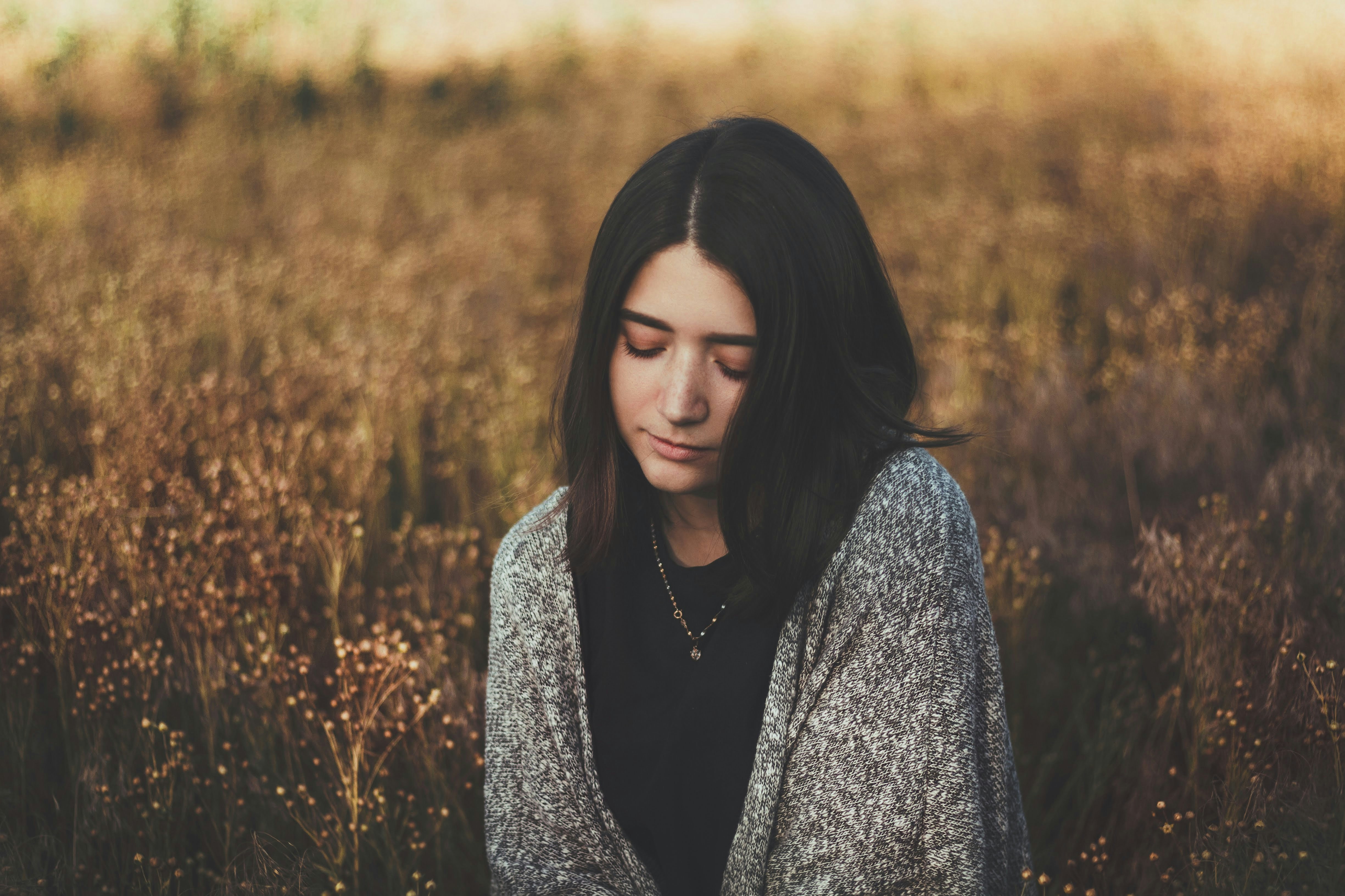 woman in black and white floral long sleeve shirt standing on brown grass field during daytime