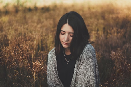 woman in black and white floral long sleeve shirt standing on brown grass field during daytime