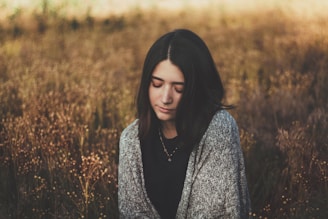 woman in black and white floral long sleeve shirt standing on brown grass field during daytime