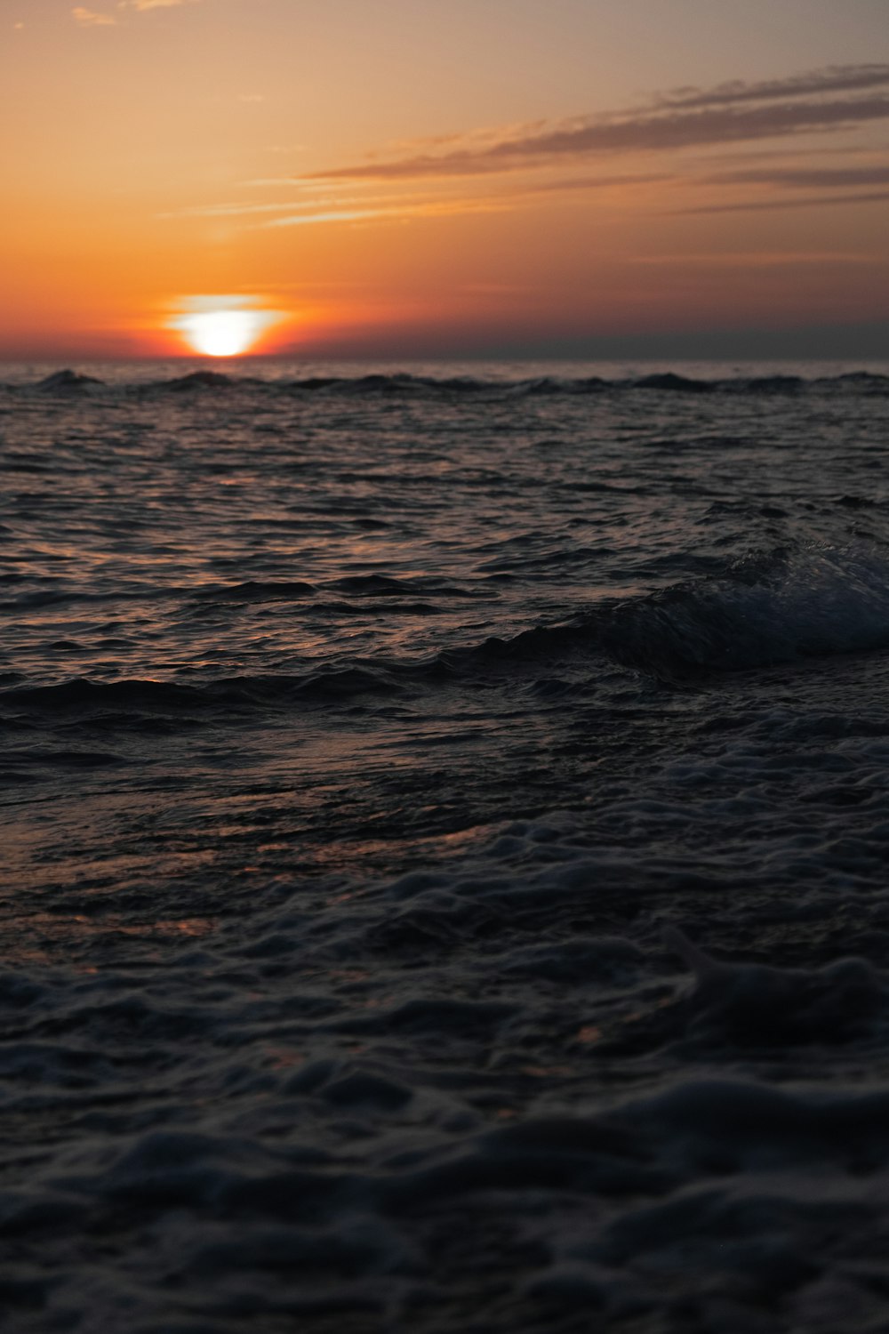 ocean waves crashing on shore during sunset