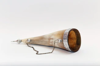 An ornate Viking drinking horn filled with a frothy, amber-hued beverage.