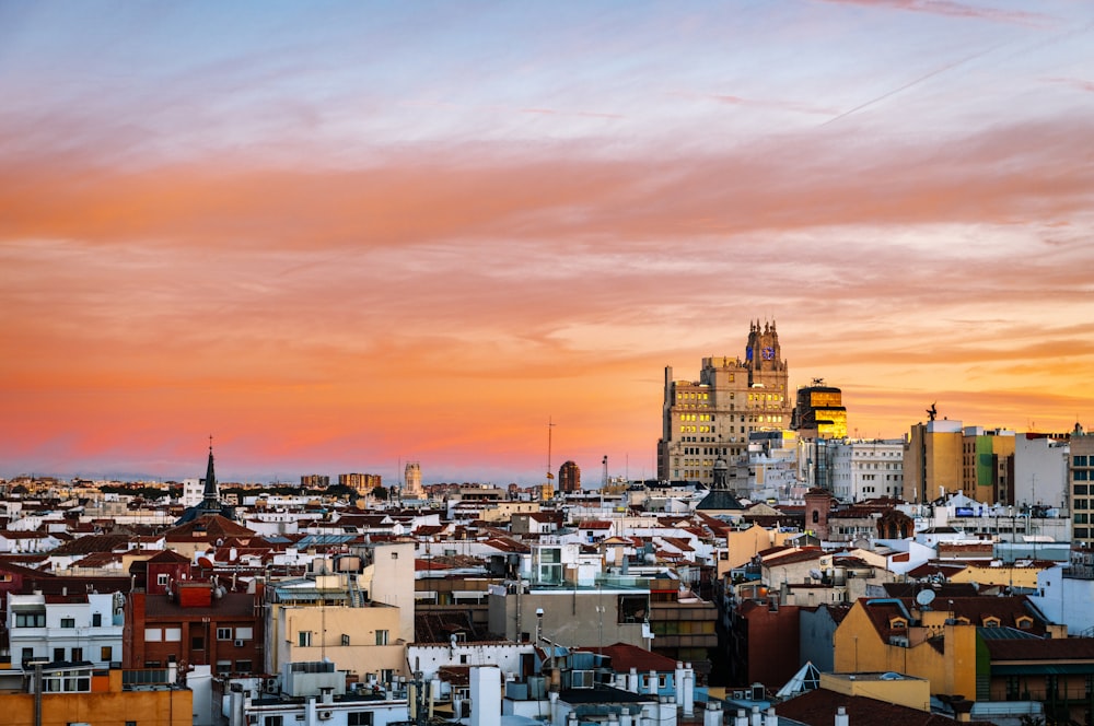 Ciudad con edificios de gran altura bajo cielos anaranjados y grises durante la puesta del sol