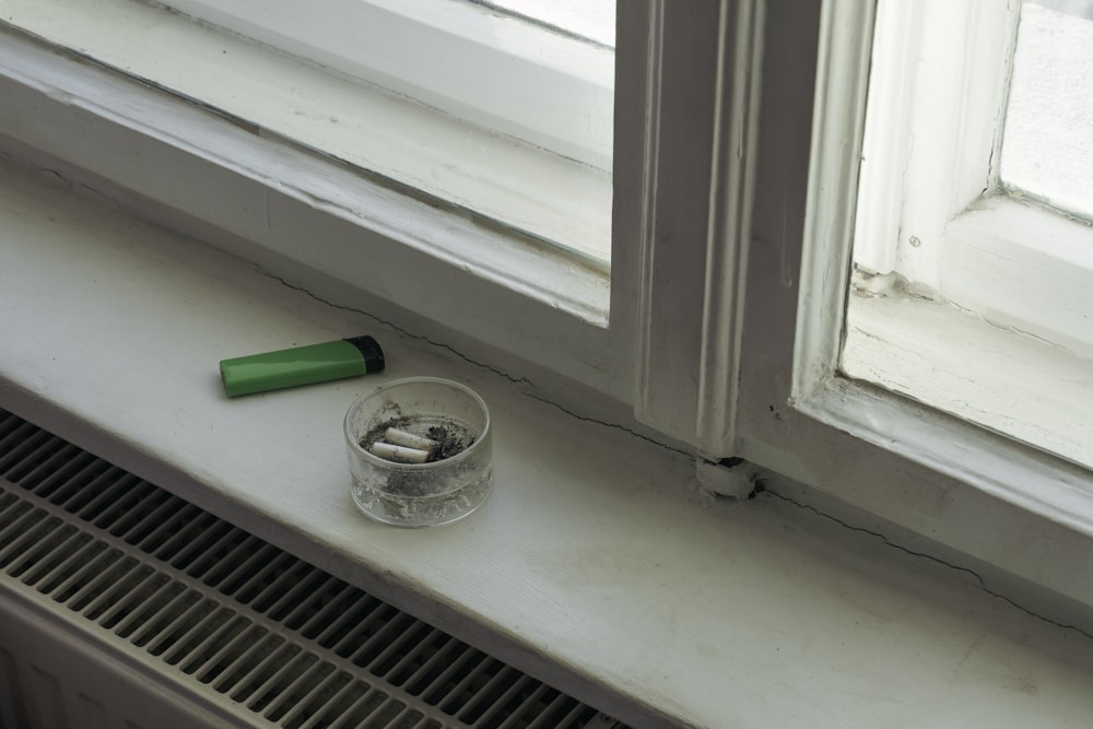 clear glass ashtray beside green disposable lighter