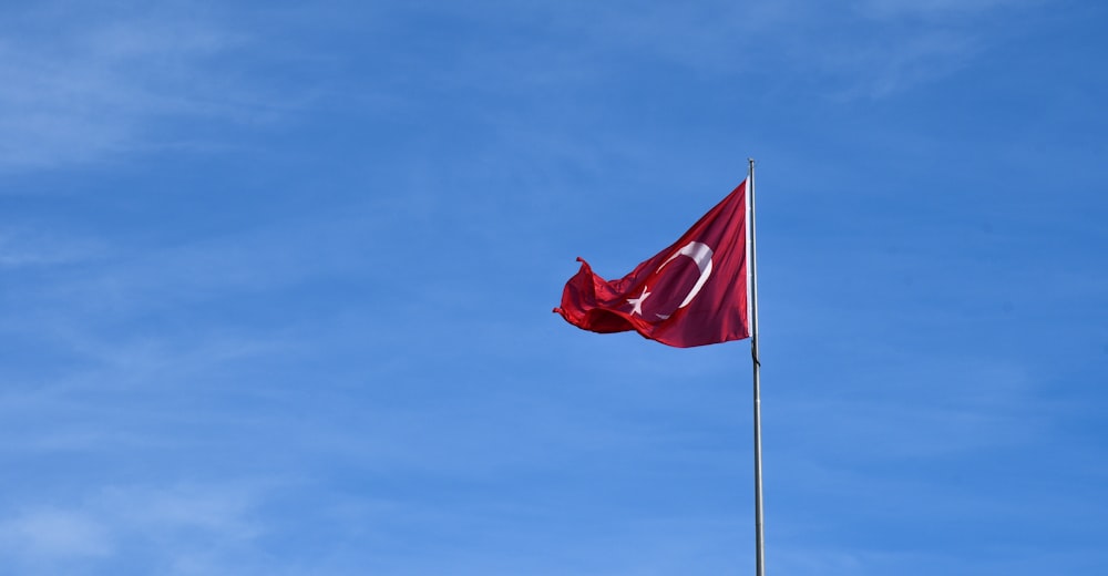 Bandera roja y blanca bajo el cielo azul durante el día