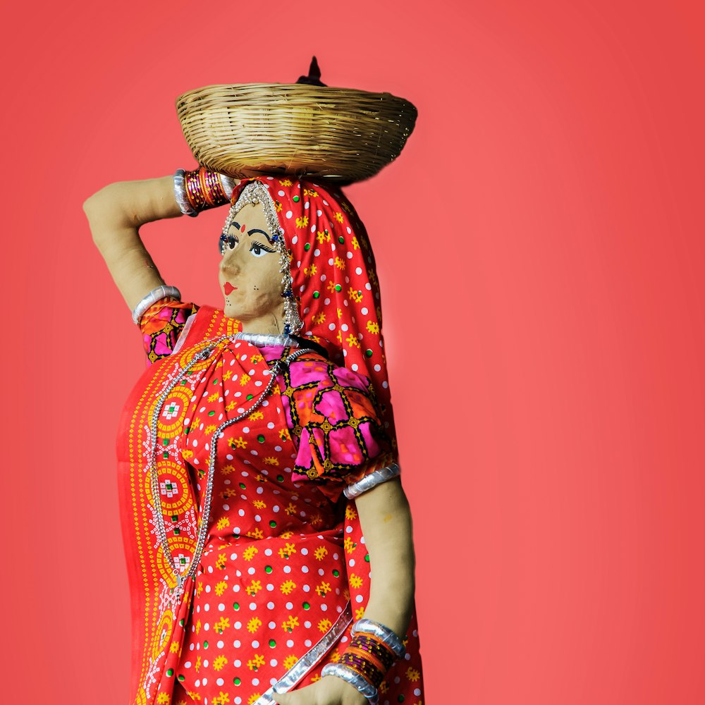 Mujer en sari floral rojo y verde sosteniendo canasta tejida marrón