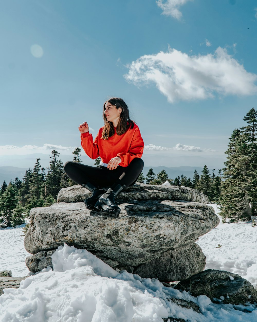 woman in red jacket sitting on rock formation during daytime