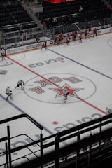 Young athletes practicing ice hockey on an indoor rink with coaches guiding them.