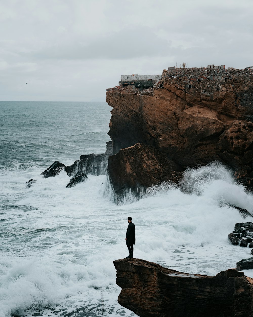 person standing on rock formation near sea during daytime