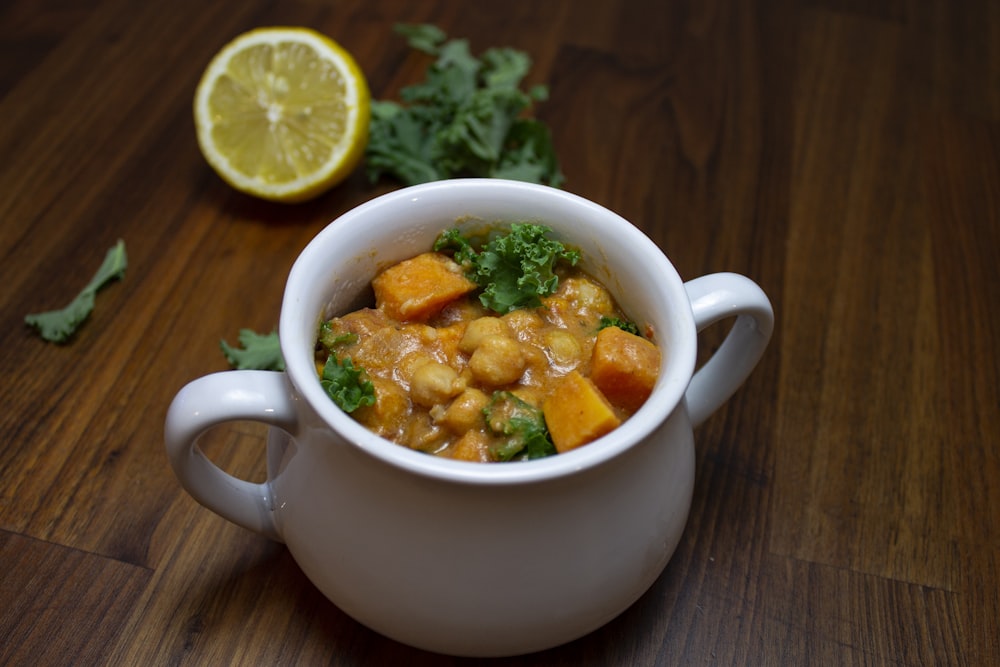 a bowl of food on a table next to a lemon