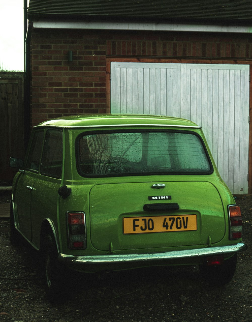 green sedan parked beside brown brick building