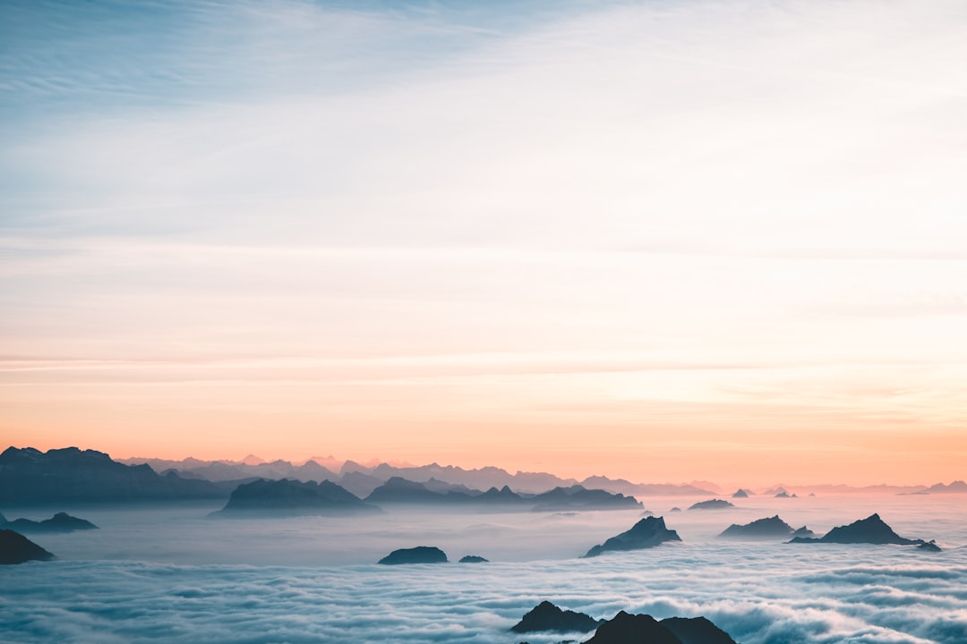 silhouette of mountain near body of water during sunset