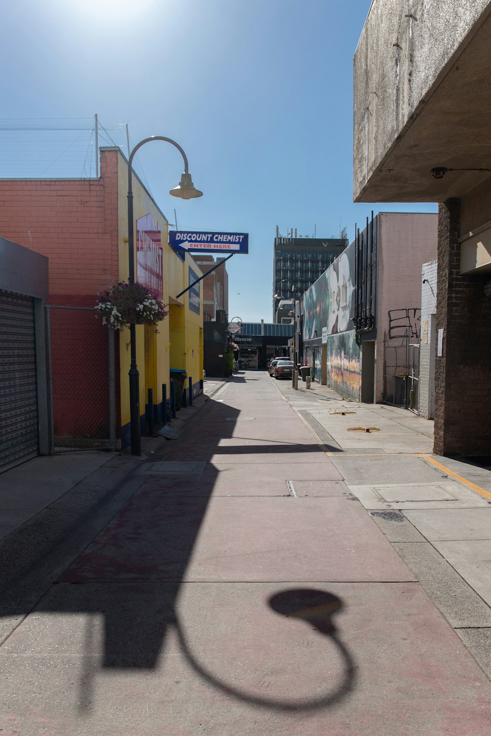 empty street with cars parked beside buildings during daytime