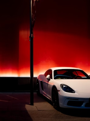 Red sports car angled dynamically against a clean white wall.