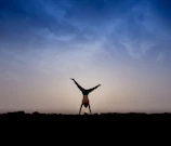 A powerful handstand held confidently against a clear blue sky.