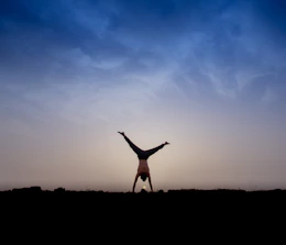 An athletic man mastering a challenging calisthenics move outdoors at sunset.